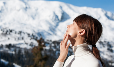 Woman Applying Sunscreen In Front of Snow Mountains